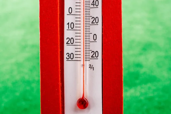 Um termômetro de plástico vermelho no fundo verde — Fotografia de Stock