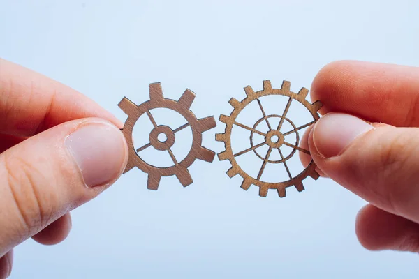 Two hands connects two round gear wheels — Stock Photo, Image