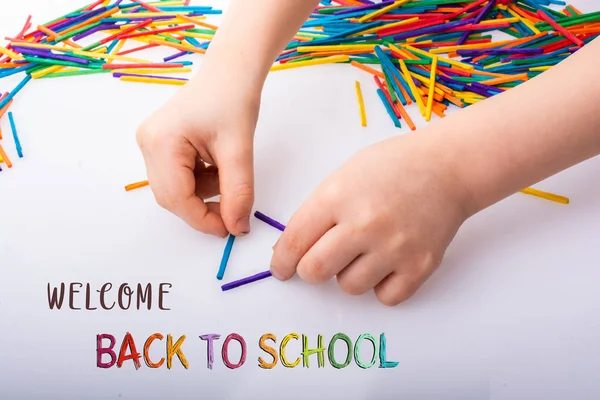 Çocuk beyaz backgr üzerinde renkli çubuklarla geometrik şekiller yapmak