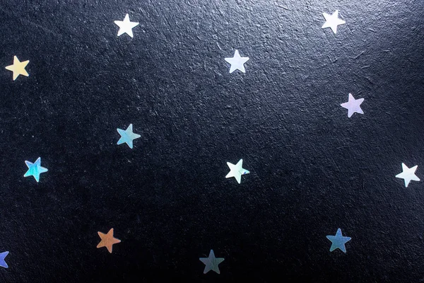 Coloridas estrellas de confeti sobre un fondo de color oscuro —  Fotos de Stock