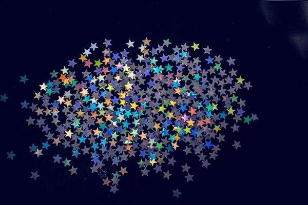 Coloridas estrellas de confeti sobre un fondo de color oscuro — Foto de Stock