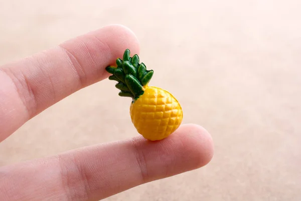 Main tenant une petite miniature d'ananas sur un fond — Photo