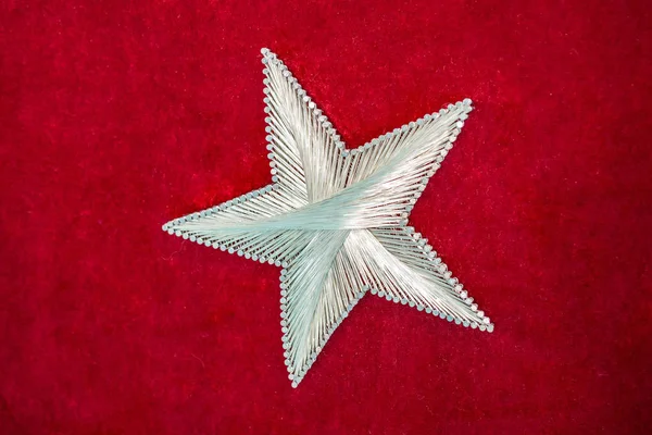 A star made from steel nails and string on red background