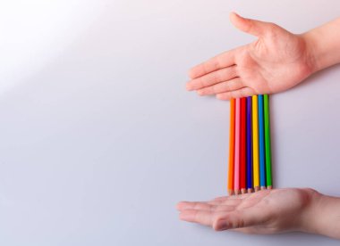 Beyaz arkaplana yerleştirilmiş el ele tutuşan kalemler