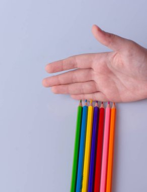 Hand holding color Pencils placed on a white background