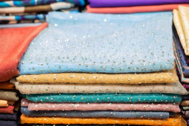 Bir pazarda çok renkli kumaş yığını.