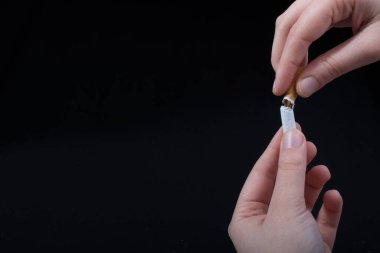 El siyah arka planda sigara kırıyor.