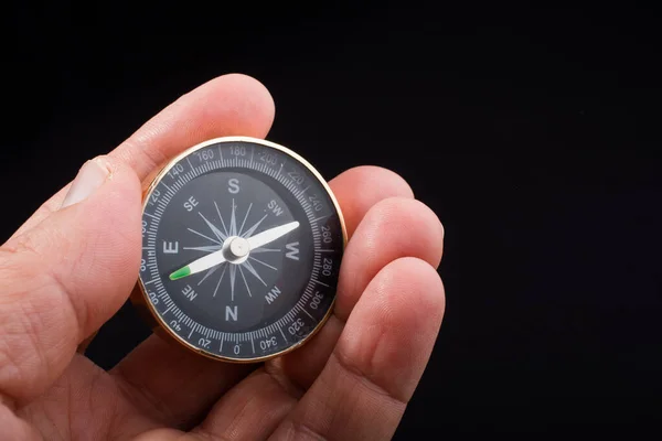 Child hand holding a compass  on a  black background