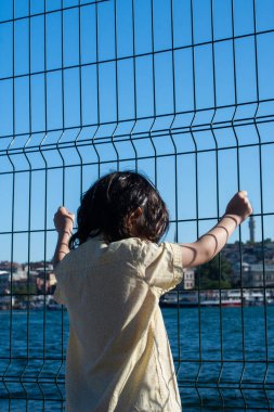 Çitin arkasında İstanbul camisi olan düşünceli küçük çocuk.
