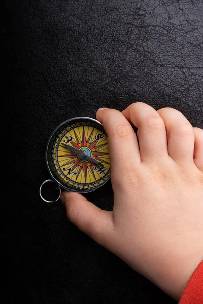 Hand is holding a magnetic compass on black background