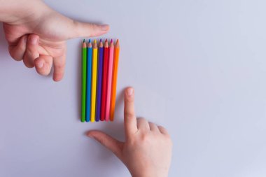 Beyaz arkaplana yerleştirilmiş el ele tutuşan kalemler