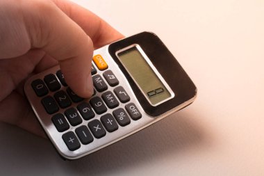 Elinde klavyesi ve ekranı olan elektronik hesap makinesi.