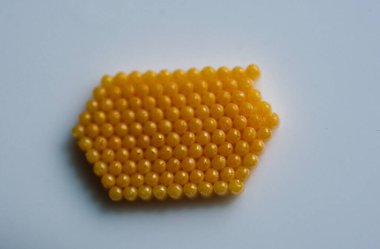 Sarı renkli böcek yumurtaları beyaz arka planda neredeyse mükemmel bir altıgen oluşturuyor.