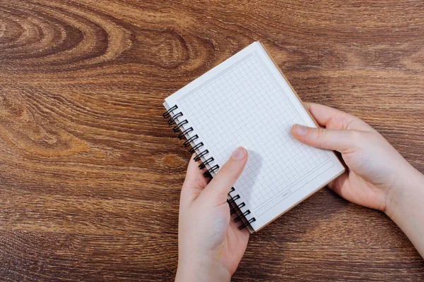 White notebook in hand on  a brown color background