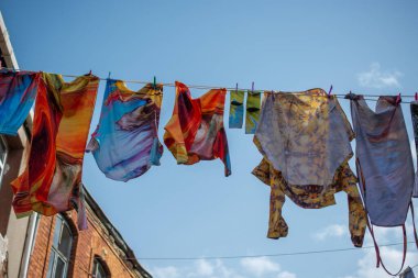 Elbiseler bir ipte sallanıyor sokakta.