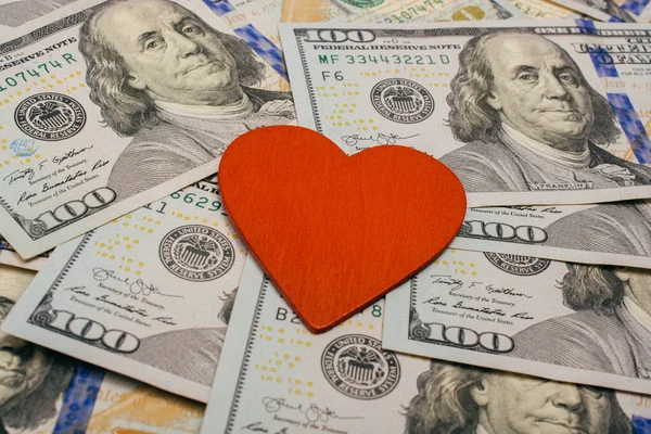 Red heart lies on dollar bills.  Concept of selling love for money