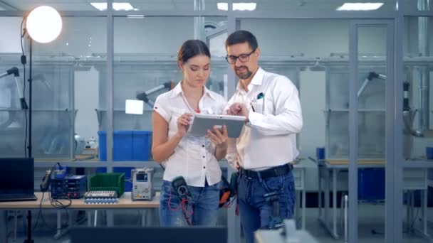 Female and male engineers are discussing something with a tablet computer — Stock Video