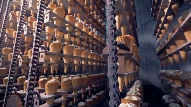 Заводской механизм поднимает и опускает ряды вафельных шишек с мороженым — стоковое видео