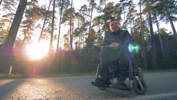 Un hombre se sienta en una silla de ruedas negra . — Vídeos de Stock