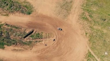 Adam sürücüler kumlu bir yolda, üstten görünüm.