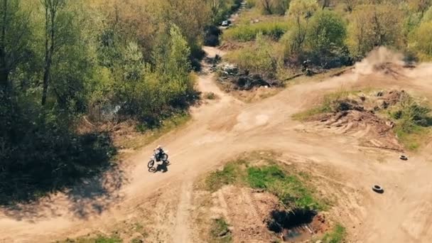 En motocrossförare hoppar på en kulle, ovanifrån. — Stockvideo