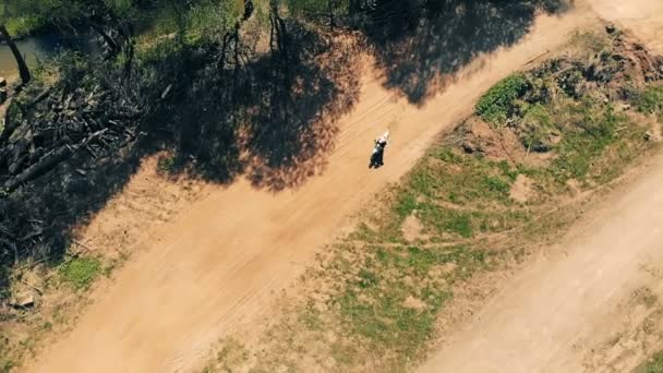 Motociclista maschio cavalca su una pista polverosa, vista dall'alto . — Video Stock