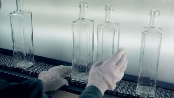 Работник завода трогает и перемещает стеклянные бутылки вдоль конвейера — стоковое видео