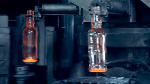 Формовочные стеклянные бутылки выпускают через стеклоформовочную машину — стоковое видео