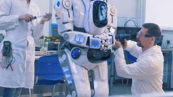Två ingenjörer reparerar en människoliknande robot — Stockvideo
