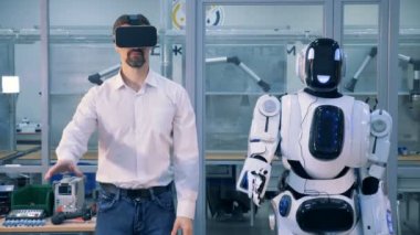 Bir insan benzeri robot ve bir adam synchronically farklı bölümlerini vücutlarını hareket ediyor