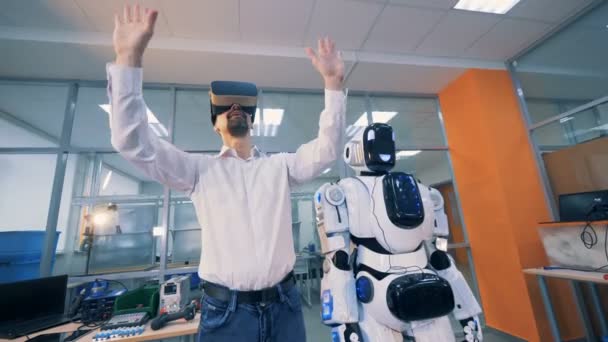 Ingeniero masculino está de pie junto a un cyborg y manipulando la realidad virtual a través de gafas — Vídeos de Stock
