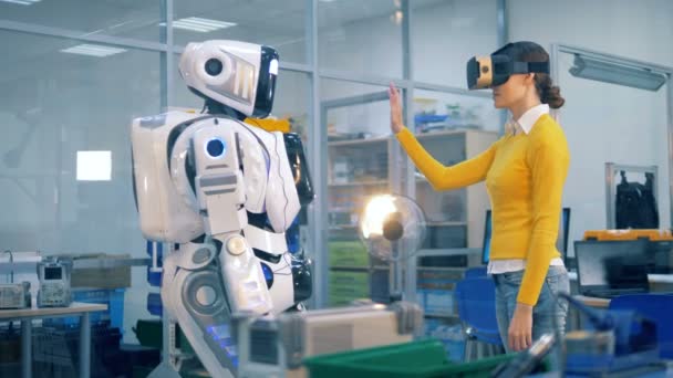 Роботизированный гуманоид дает пять даме в очках виртуальной реальности — стоковое видео
