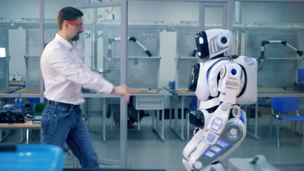Robot humano está siendo empujado por un ingeniero masculino y caminando de vuelta a él — Vídeo de stock