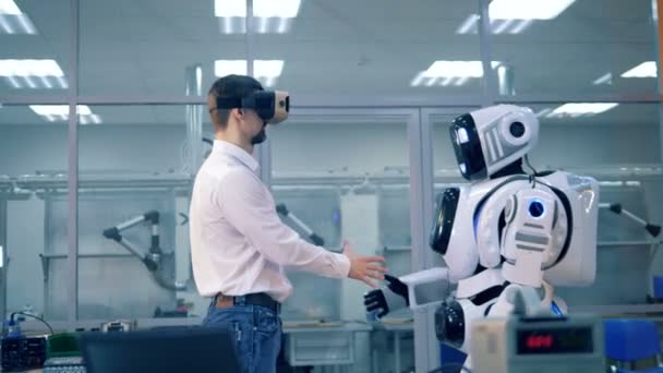 Un humano y un androide parecido a un humano están estrechando la mano y viendo la realidad virtual — Vídeo de stock