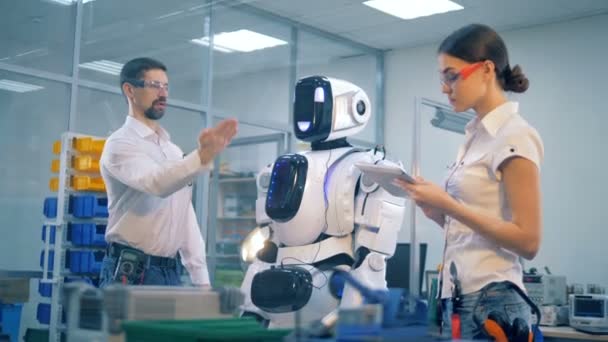 Homme ingénieur montre des gestes pour contrôler un cyborg à son collègue féminin — Video