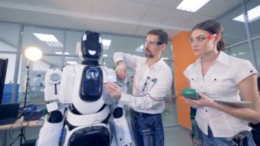 İnsanlar bir amper metre ile bir robot üzerinde çalışıyor..