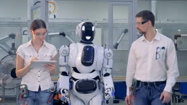Ingenieurs wandeling samen met een robot. — Stockvideo
