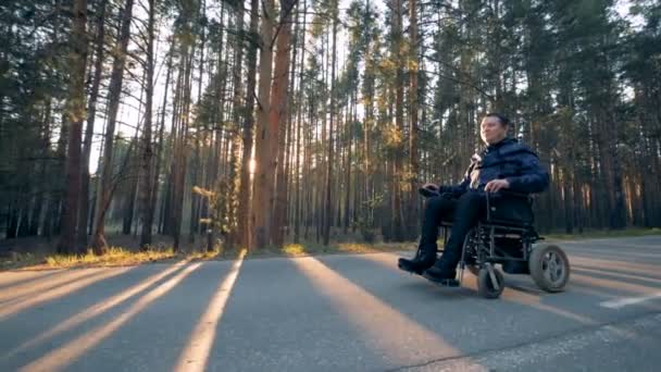 Proceso de desplazamiento de una persona con discapacidad en una silla de ruedas al aire libre — Vídeo de stock