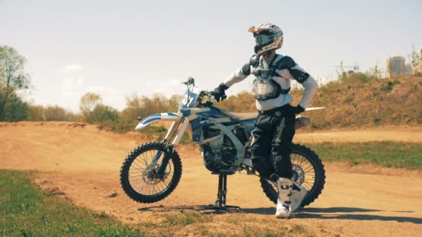 Мотоциклист и его мотоцикл стоят посреди пыльного ландшафта — стоковое видео