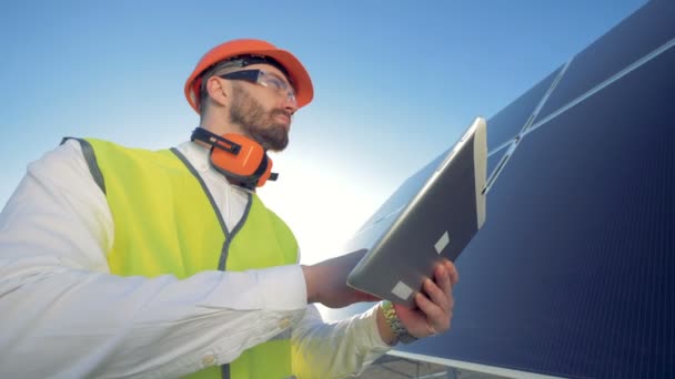 Conceito de energia verde. Engenheiro está trabalhando com seu computador tablet e olhando para uma bateria solar — Vídeo de Stock