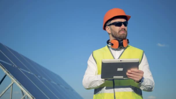 Proceso de trabajo de un inspector masculino de pie con una computadora cerca del panel solar — Vídeos de Stock