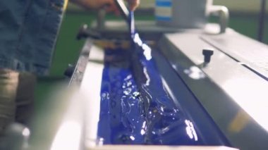 Bir adam kalın mavi boya fabrika baskı makinesi özel bir birim içinde bırakır..