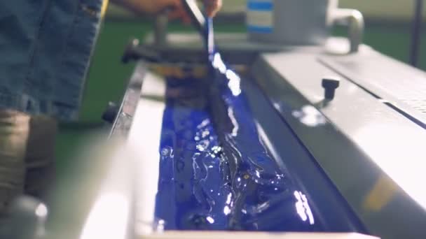 Ein Mann legt dicke blaue Farbe in eine Spezialeinheit einer Fabrikdruckmaschine. — Stockvideo