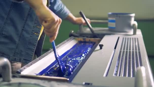 Άνδρας εργαζόμενος χρησιμοποιεί μια βούρτσα για να ακόμη και ένα στρώμα από ένα μπλε χρώμα σε ένα ειδικό τμήμα μιας μηχανής. 4k. — Αρχείο Βίντεο