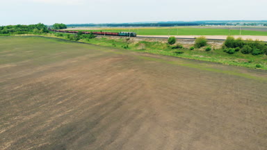 Uzun bir yük treni bir demiryoluna gider. Havadan görünümü.