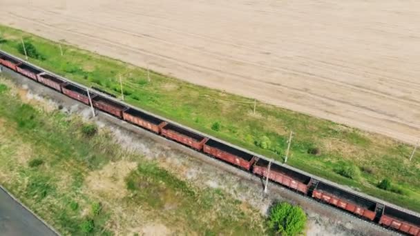 Um trem de carga se move em uma ferrovia, vista aérea. Comboio de mercadorias com contentores de carga a passar — Vídeo de Stock