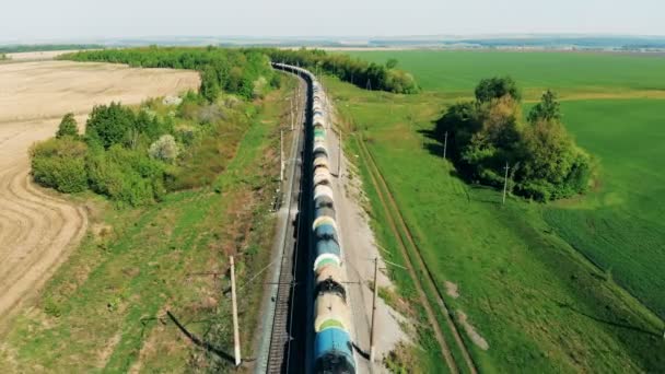 Treno merci con carri cisterna va su una lunga ferrovia vicino ai campi. 4K . — Video Stock