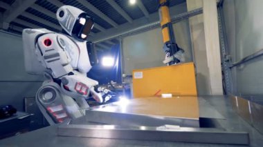 İnsan benzeri robot kaynakçı bir fabrikada, metal bir plaka kaynak.