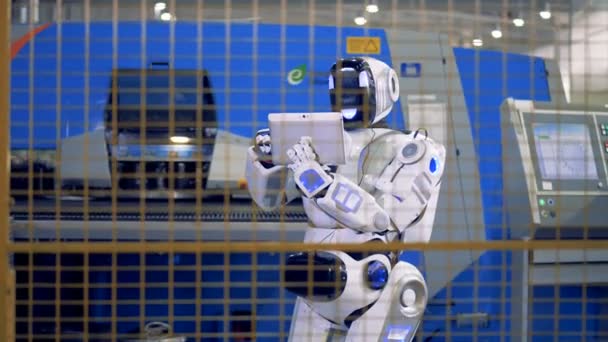 Robot industrial, cyborg que gestiona el proceso de trabajo con una computadora en una fábrica . — Vídeo de stock