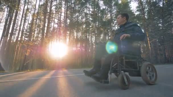 Un homme handicapé se déplace dans un fauteuil roulant motorisé le long de la route — Video